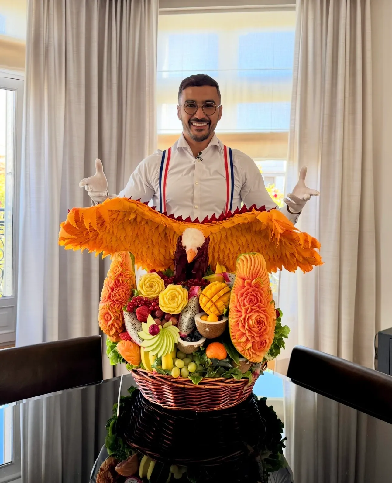 Atef Barbouche derrière une pièce monumentale : un aigle aux ailes ciselées au-dessus d'une corbeille de fruits sculptés en roses.
