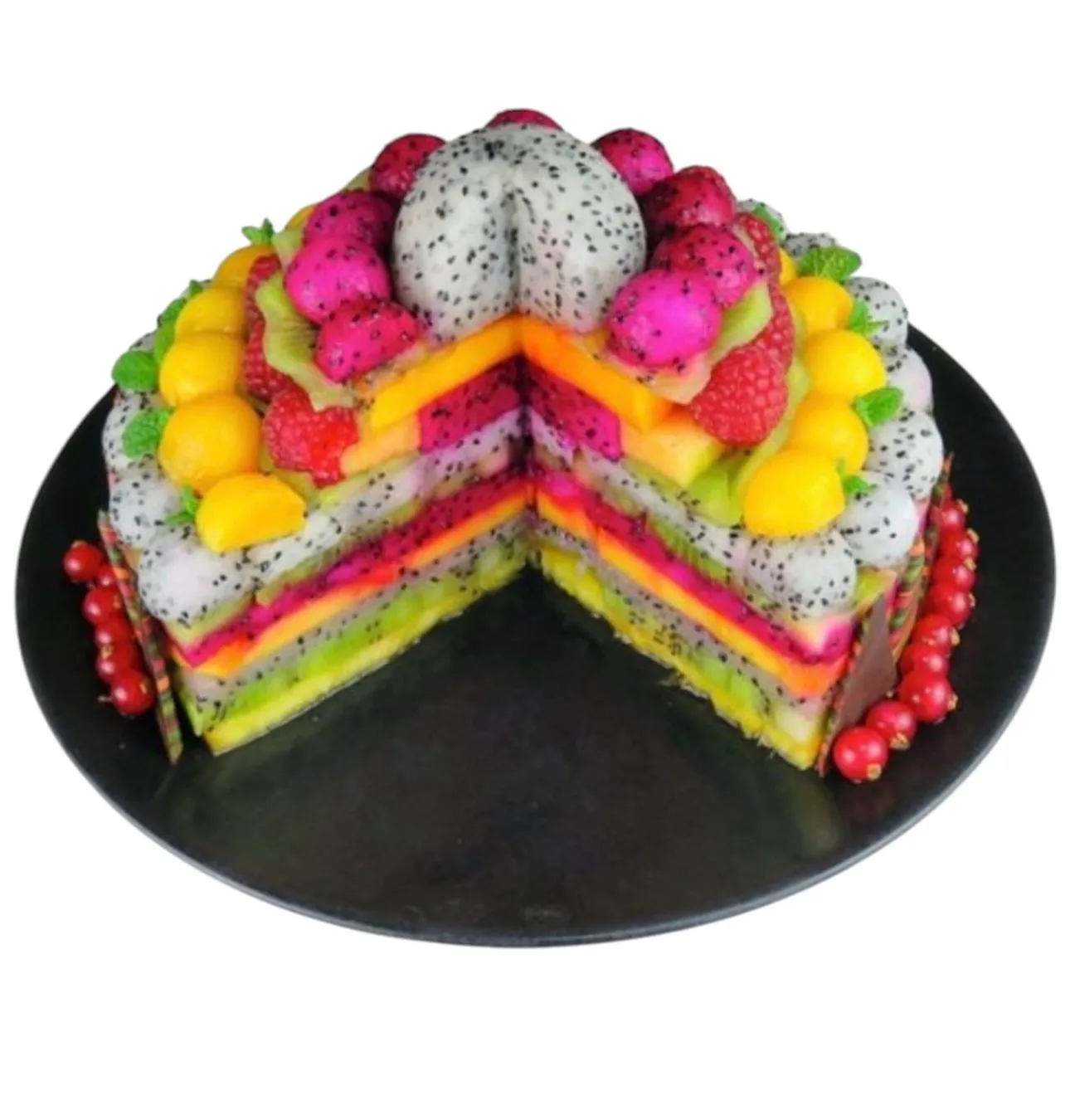 Gâteau de fruits en coupe : dôme de pitaya blanc, billes de pitaya rose et de mangue, framboises, strates colorées de fruits, groseilles sur plateau noir.